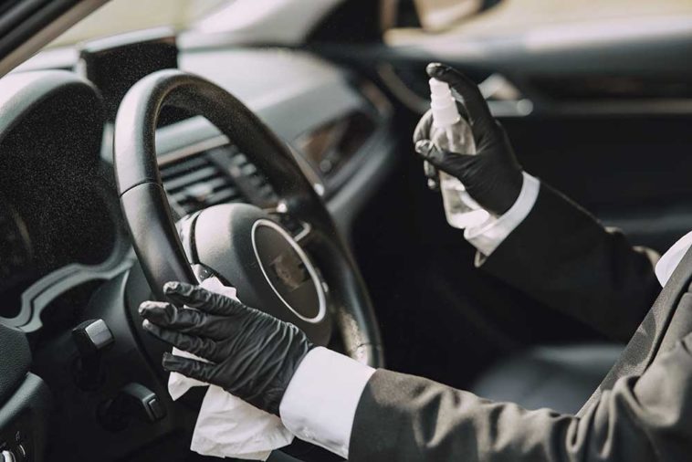 Personne désinfectant et nettoyant l'intérieur de la voiture avec un liquide antiseptique et des lingettes de désinfection humides. Le volant est l'une des pièces les plus sales de la voiture et peut contenir des virus et des bactéries.